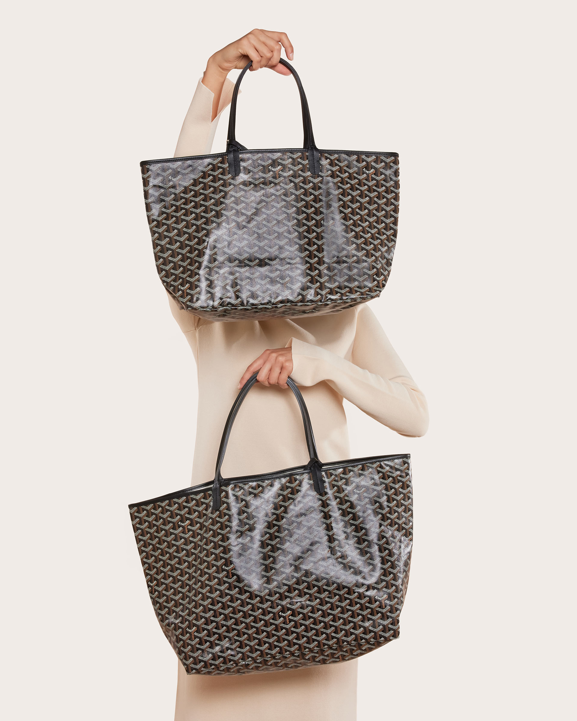 studio image of model holding two Goyard St Louis tote bags FASHIONPHILE